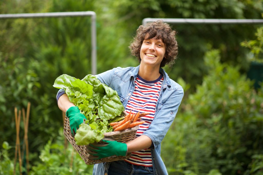 Portrait of female farmer smiling with bunch of vegetables in basket