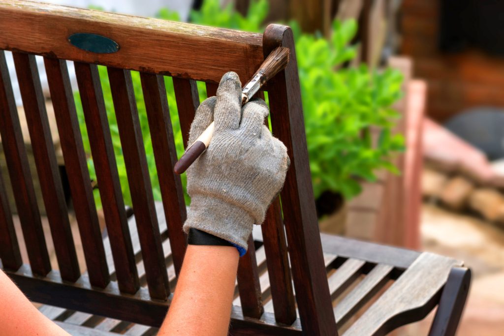 Painting and applying protective varnish on a wooden garden chair