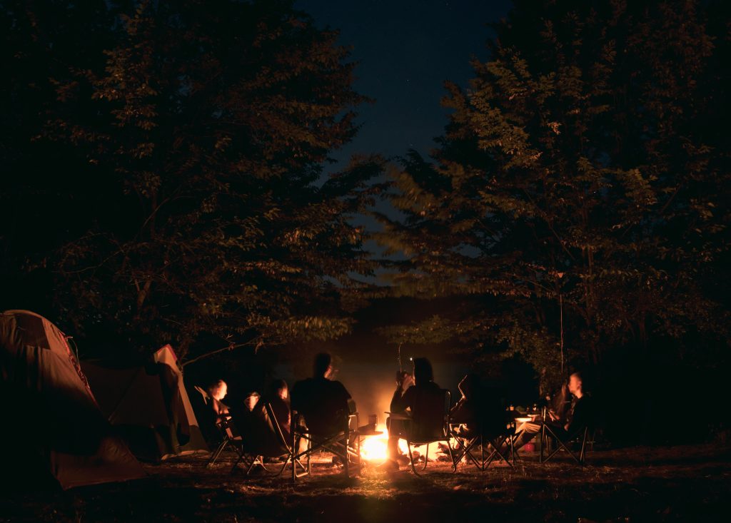 The group of young people are sitting around the bonfire and talking and singing songsup of young people are sitting around the bonfire and talking and singing songs