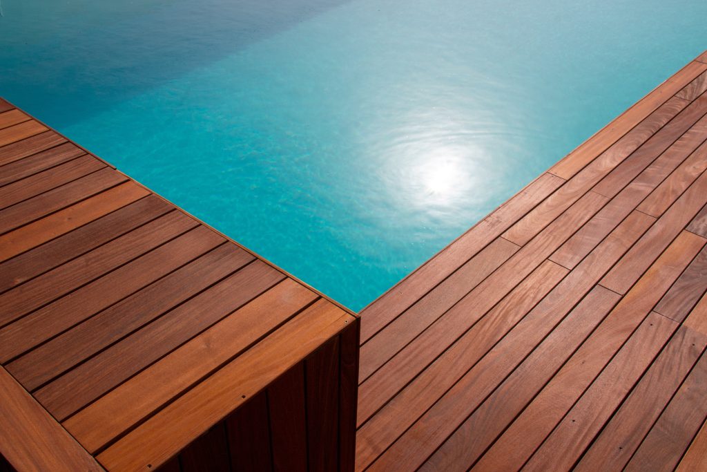 Diagonal lines of wood in detail decking and blue water swimming pool abstract background